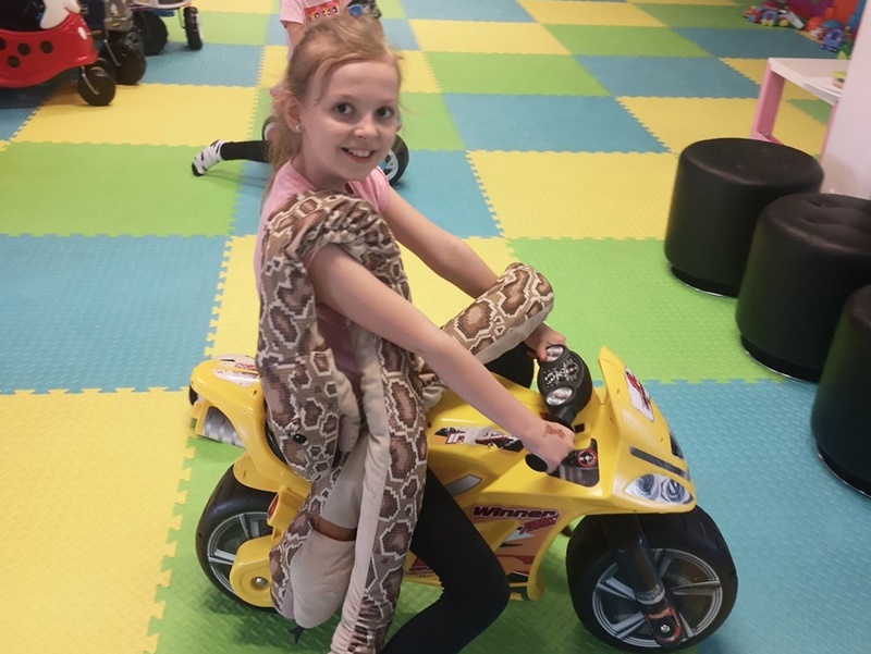 Dziewczynka na żółtym skuterze-zabawce