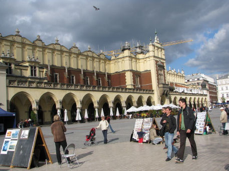 Grupa uczniów stoi na krakowskim Rynku. W tle widać Sukiennice.